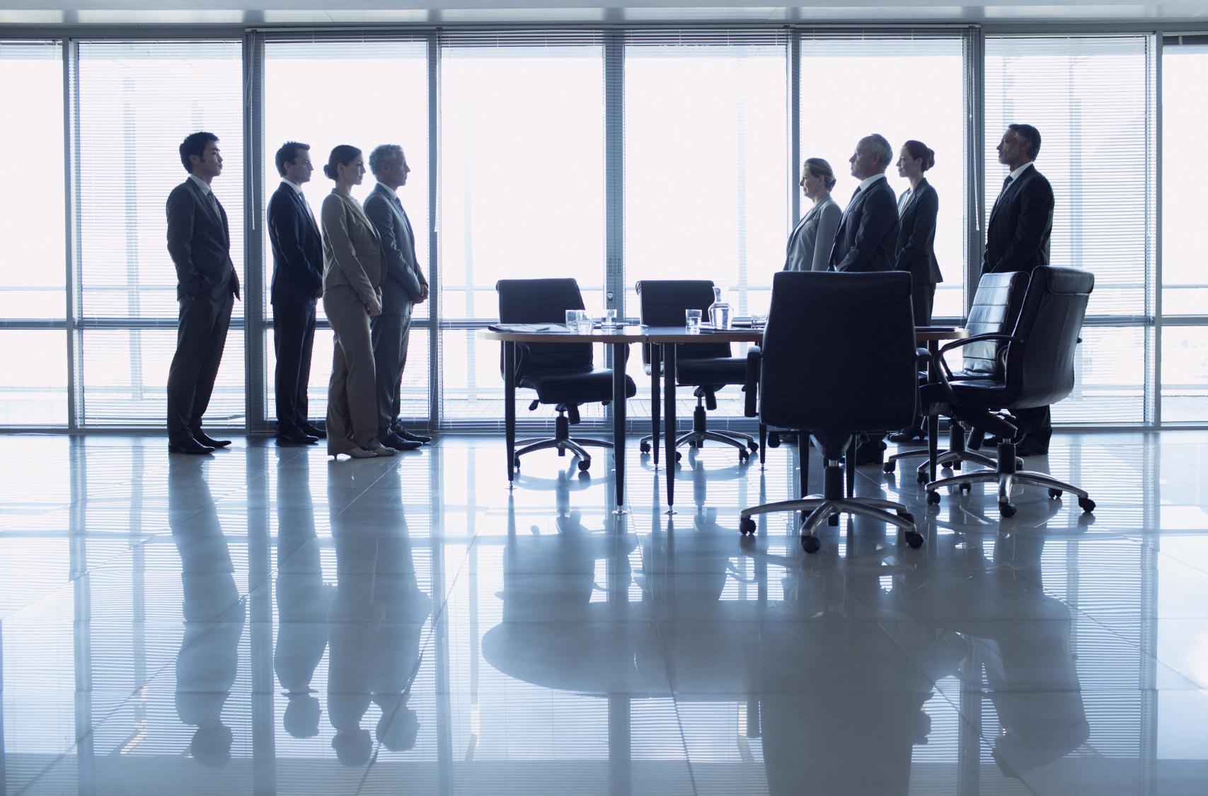 Separate groups of business people facing off in conference room
