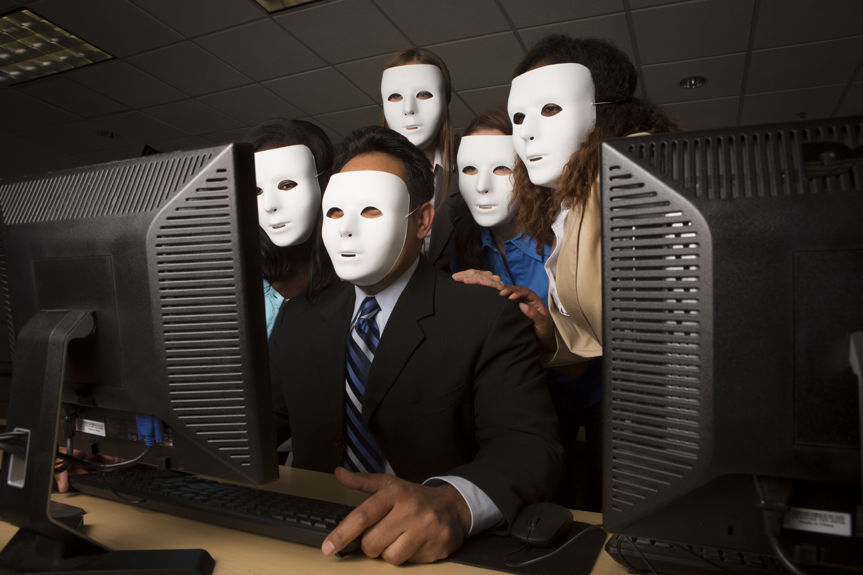 Anonymous Computer Activist gather around a computer monitor