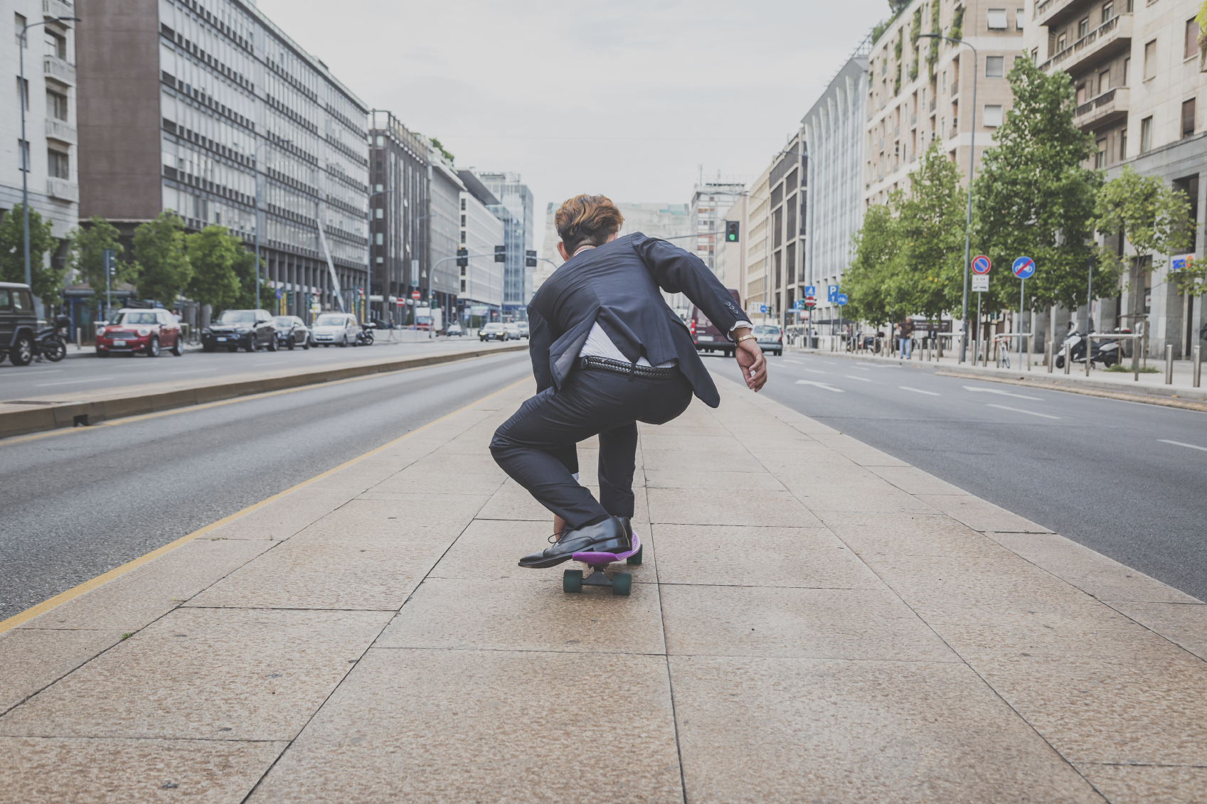 Young handsome Asian model dressed in dark suit and tie riding his skateboard