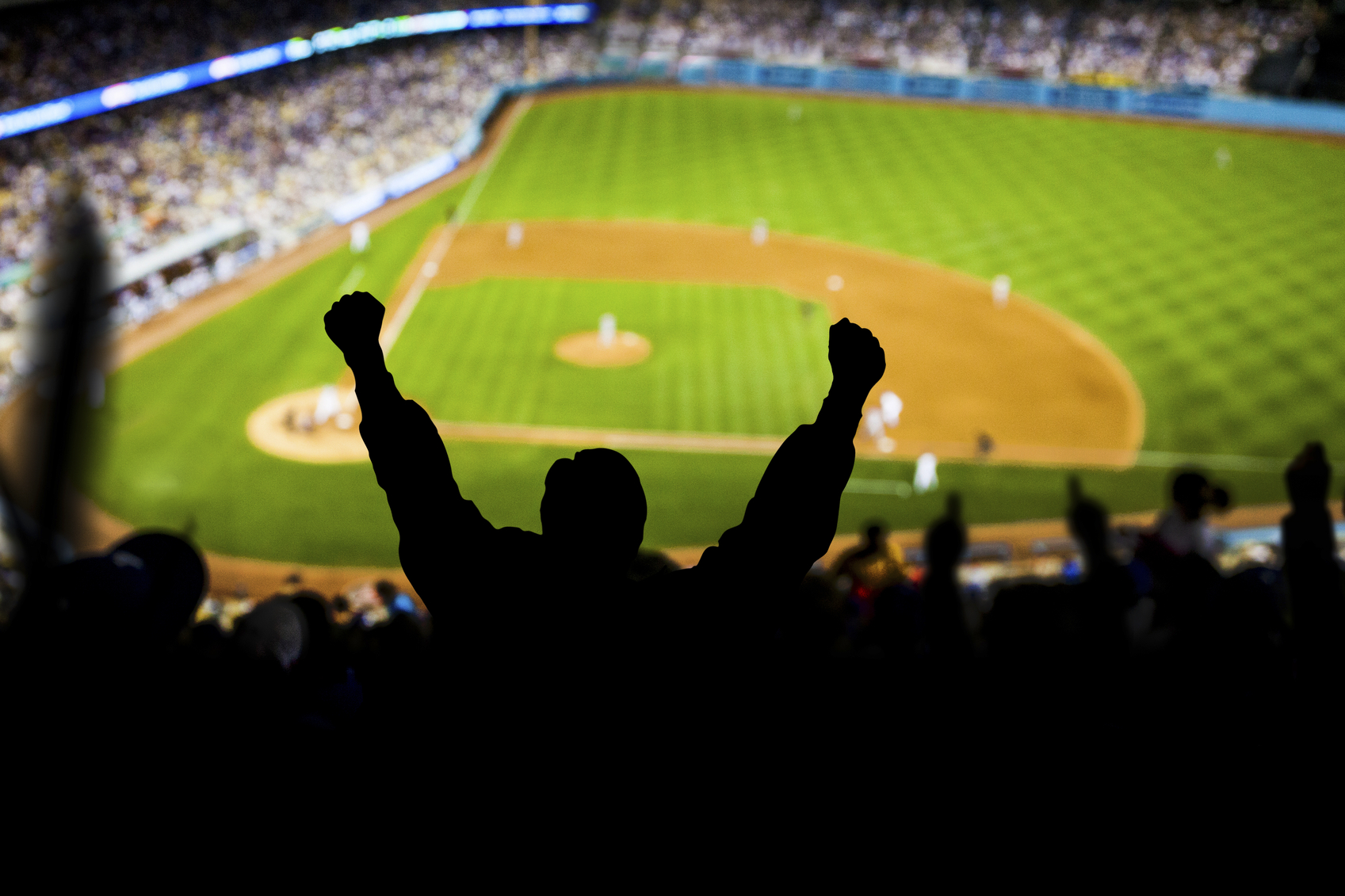 Fans raise their hands in excitement at a baseball game.