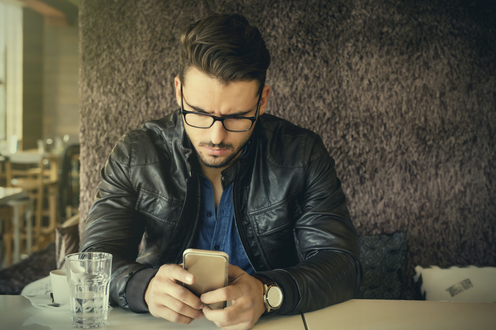 Handsome man with eyeglasses and leather jacket using smartphone