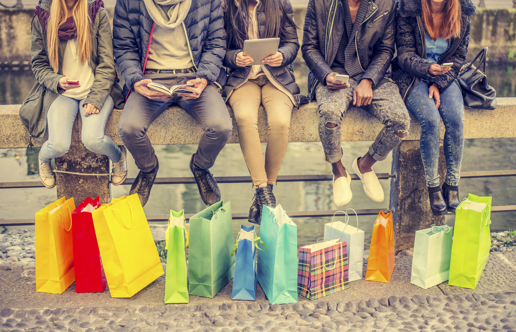 Group of friends sitting outdoors with shopping bags - Several people holding smartphones and tablets - Concepts about lifestyle,shopping,technology and friendship