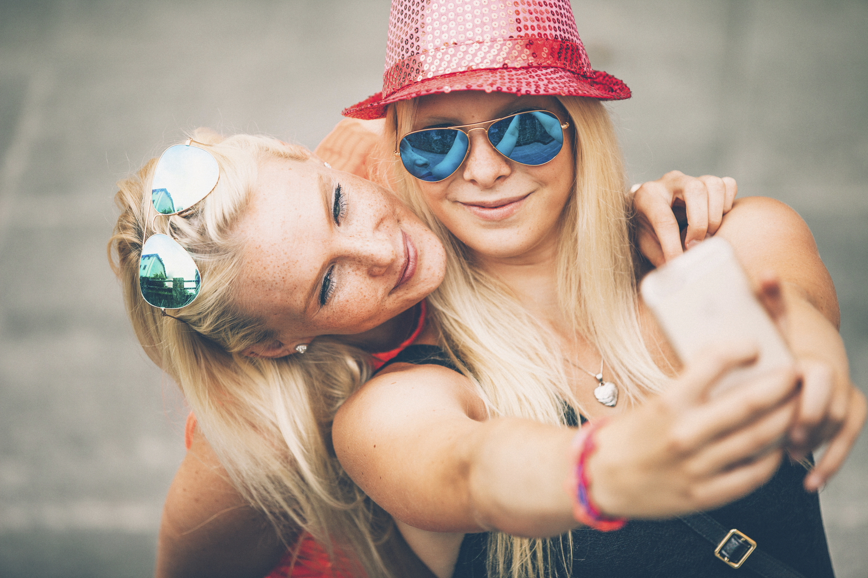 Two beautiful Caucasian women with Sunglasses taking cell phone selfie outdoors in the summer, scandinavian women